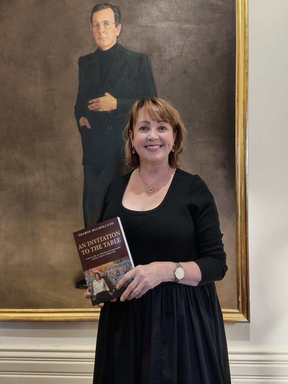 Author Sharon Mulholland holding a copy of An Invitation to the Table
